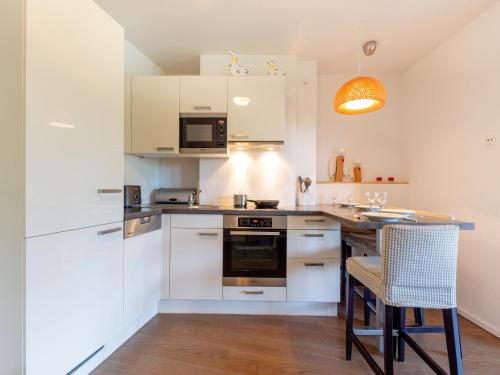 eine Küche mit weißen Schränken und einem Tisch und Stühlen in der Unterkunft Apartment in Mittersill near Ski Bus & Slopes in Hollersbach im Pinzgau