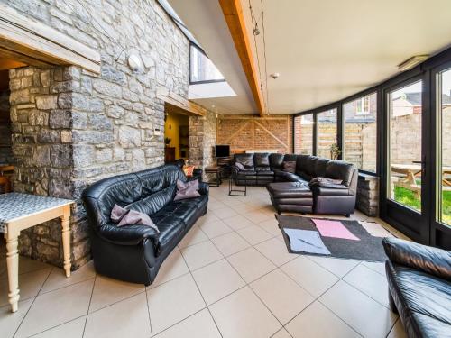 a living room with leather furniture and a stone wall at Han-sur-Lesse cottage in Han-sur-Lesse