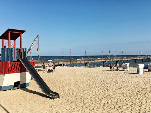 a slide on the beach with a pier in the background at 5 star holiday home in Großenbrode in Großenbrode