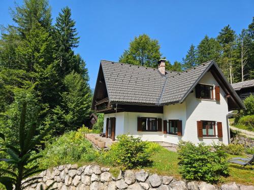 a white house with a black roof and trees at Chalet 61 Lake Jasna in Kranjska Gora
