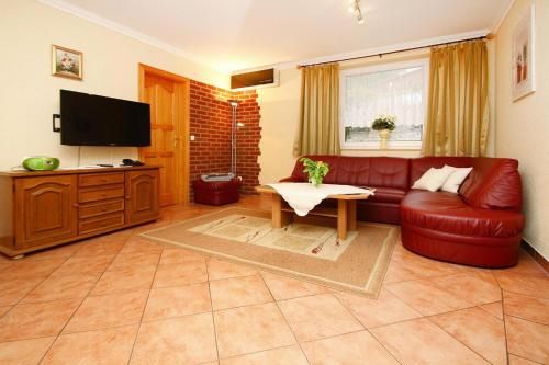 SewekowにあるFeriensiedlung Am Grundlossee in Sewekowのリビングルーム(赤い革張りのソファ、テレビ付)