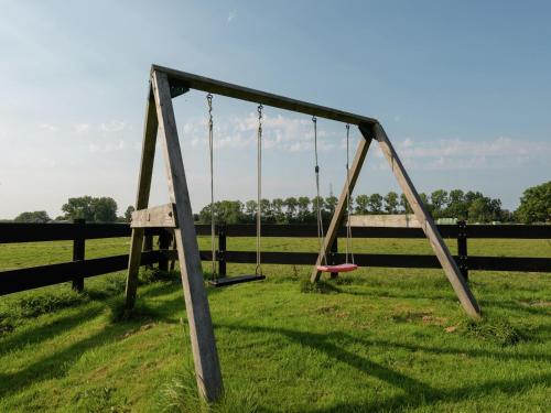a swing set in a field next to a fence at Holiday Home near Lutjestrand Beach in Oosterklief