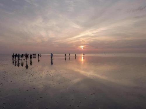 a group of people standing on the beach at sunset at Holiday Home near Lutjestrand Beach in Oosterklief
