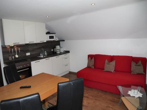 a living room with a red couch and a table at Flat in Krimml with a balcony in Krimml