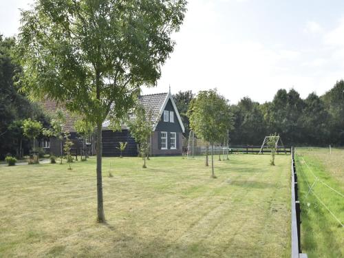 a large yard with a house and a playground at Holiday Home near Lutjestrand Beach in Oosterklief