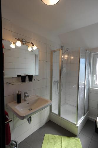 a bathroom with a glass shower and a sink at Hotel Lindas in Oyten