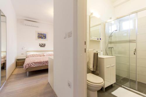 a bathroom with a toilet and a sink and a bed at Rooms Vilena in Medulin