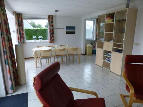a living room with a chair and a dining room at bungalow for 6 people, near the beach in Sint Maartenszee