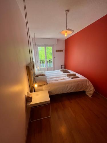 une chambre avec un grand lit avec un mur rouge dans l'établissement Bel appartement Samoëns 72m2, à Samoëns