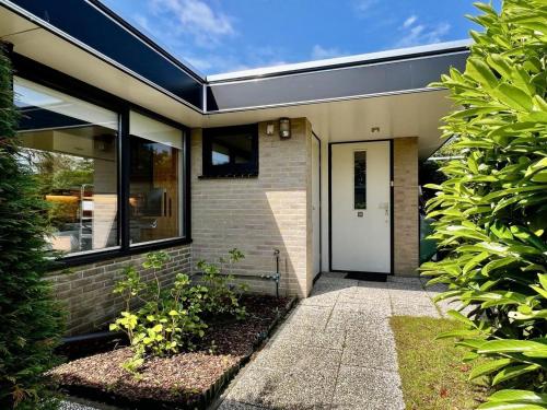 a house with a white door and some plants at Holiday home for 6 in Sint Maartenszee in Sint Maartenszee