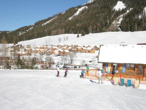 a group of people standing in the snow near a ski lodge at Chalet in Hohentauern near Ski Lift in Hohentauern