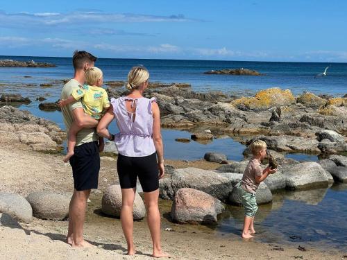 a group of people standing on the beach at Storløkke Holiday Park in Allinge