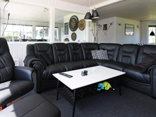 a living room with black leather couches and a table at 12 person holiday home in Hadsund-By Traum in Nørre Hurup