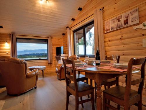 TennevilleにあるQuiet chalet with panoramic view and fenced gardenのテーブルと椅子と窓のあるダイニングルーム