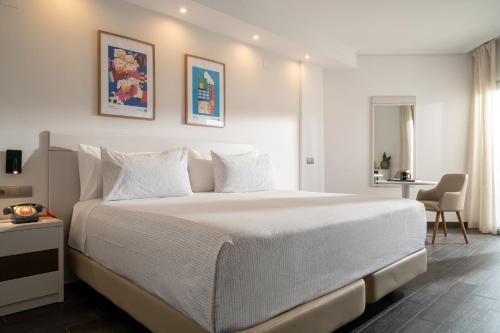 a white bedroom with a large bed and a desk at INNSiDE by Meliá Alicante Porta Maris in Alicante