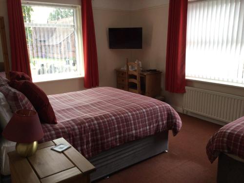 1 Schlafzimmer mit einem Bett und 2 Fenster mit roten Vorhängen in der Unterkunft Gateway Lodge in Speke