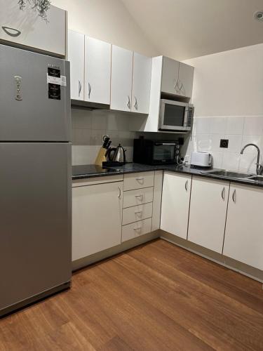 a kitchen with white cabinets and a refrigerator at River Rock Retreat in Maroochy River