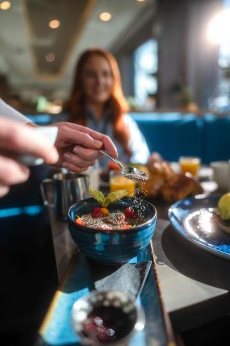 a person eating a bowl of food with a spoon at Clayton Hotel Charlemont in Dublin