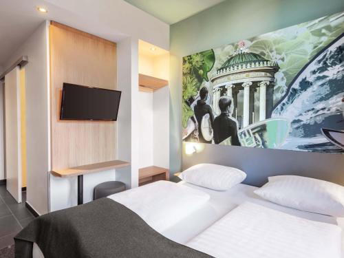 a bedroom with a white bed and a painting on the wall at B&B Hotel München-Trudering in Munich