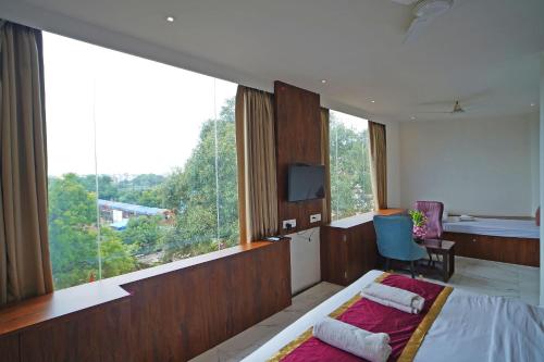 a bedroom with a bed and a large window at Hotel Tripka Square - walking distance from Baidyanath Dham Temple in Deoghar