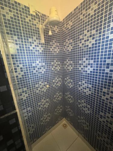 a blue tiled bathroom with a shower with a shower head at Hotel beleléus Jericoacoara in Jericoacoara