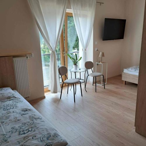 a bedroom with a table and chairs and a window at Niwy8Rooms in Oświęcim