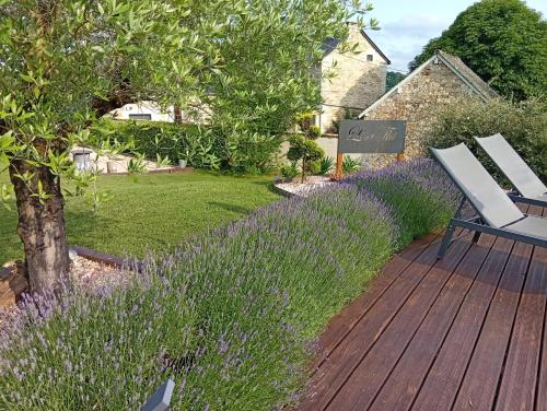 a wooden deck with two chairs and purple flowers at Lili de La LisaThi in Cruéjouls