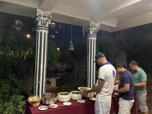 a group of men standing around a table with food at Eco Resort in Dhulikhel
