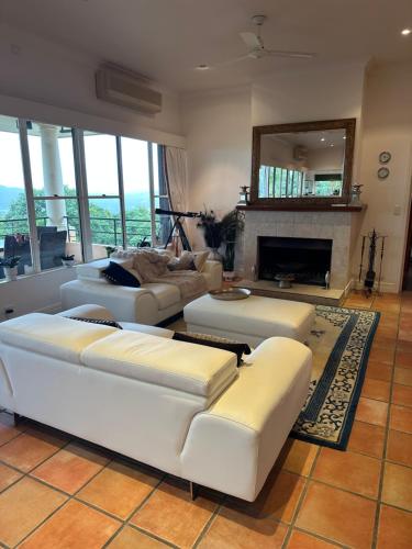 a living room with white couches and a fireplace at River Rock Retreat in Maroochy River