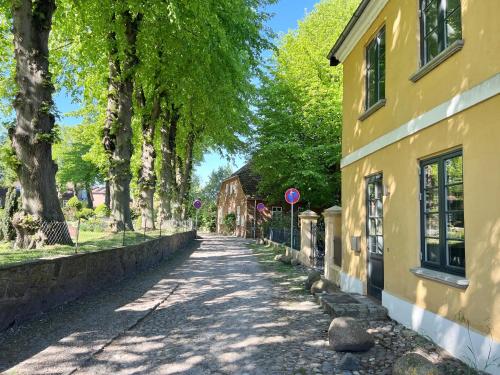 a tree lined street next to a yellow building at Villa Nikolaj - Historisches Pastorat in Fehmarn