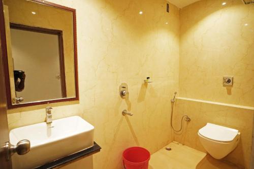 a bathroom with a sink and a toilet and a mirror at Hotel Tripka Square - walking distance from Baidyanath Dham Temple in Deoghar