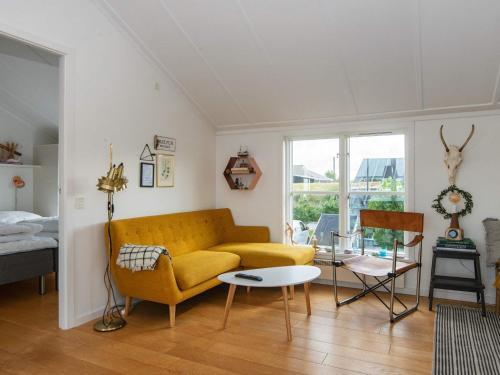 a living room with a yellow couch and a table at Islands Maritime Holiday Village Ebeltoft in Ebeltoft