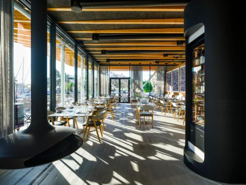 a restaurant with tables and chairs and large windows at Boutique Guesthouse - Marina Monfalcone in Monfalcone