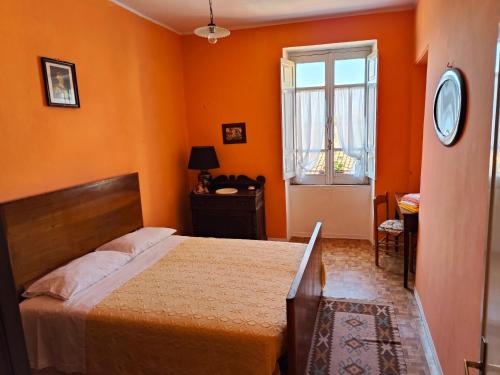 a bedroom with orange walls and a bed and a window at Casa in centro - Mormanno in Mormanno