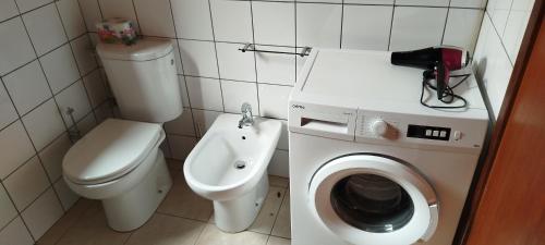 a bathroom with a toilet and a washing machine at Penthouse a stone's throw from the sea in Santa Maria
