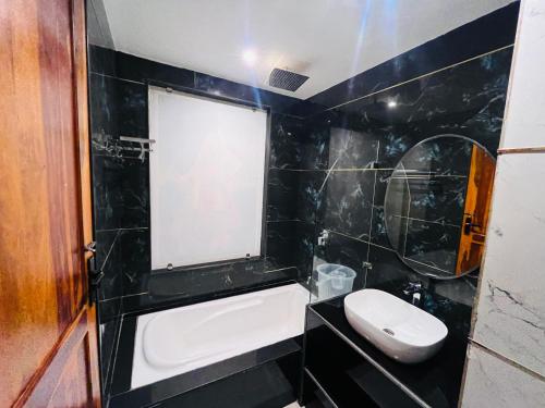 a black tiled bathroom with a sink and a toilet at Ramas Palace in Luhāra