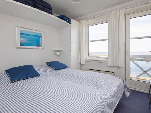 a bedroom with a bed with blue pillows and two windows at Møn - Klintholm Havn Holiday Center in Borre
