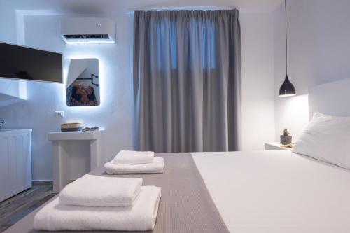 a bedroom with a white bed with two folded towels at Depis private villas Plaka Naxos in Plaka
