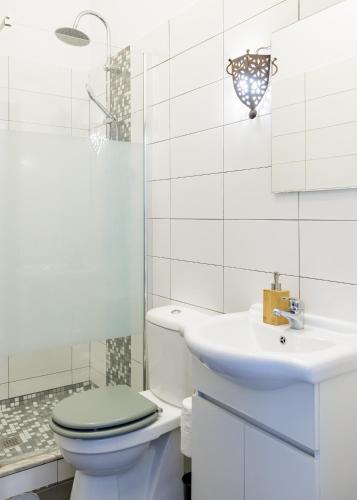 a white bathroom with a toilet and a sink at Casa 23 in Olhão