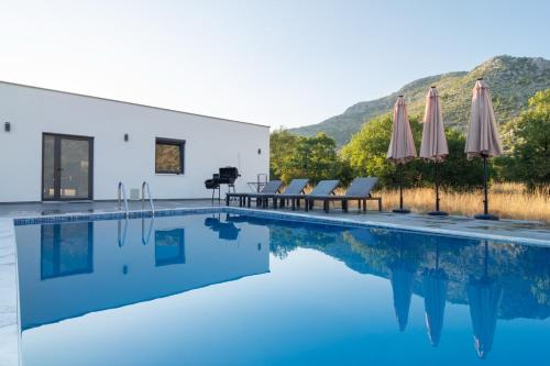 ネウムにあるVilla Leonaの建物の隣にプール(椅子、パラソル付)