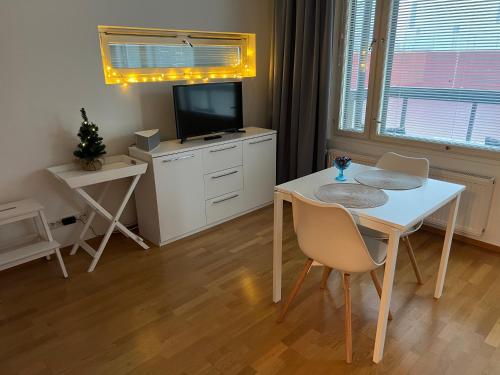 a dining room with a white table and a television at Studio next to Sello and Leppävaara train station in Espoo