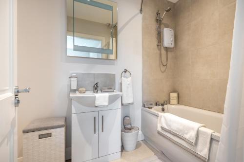 a white bathroom with a sink and a bath tub at Gardenview Manor in Moy