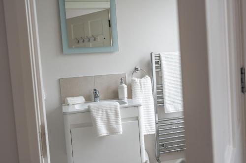 a white bathroom with a sink and a mirror at Gardenview Manor in Moy