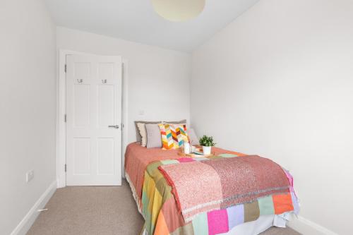 a white bedroom with a bed with a colorful blanket at Gardenview Manor in Moy