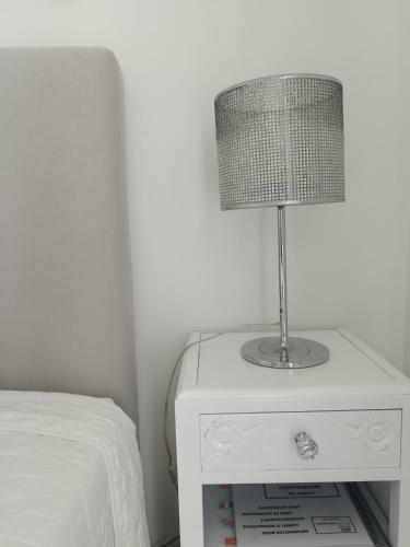 a lamp on a white nightstand next to a bed at Alexia Room in Funchal