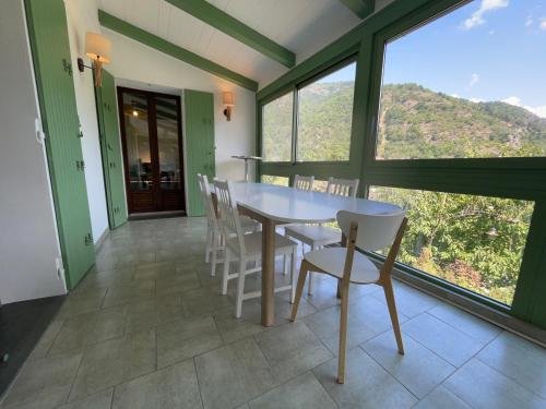 a dining room with a table and chairs and large windows at Villa fleurie - maison familiale, véranda et jardin in Tende