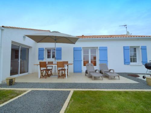 a patio with an umbrella and a table and chairs at Holiday Home in Avrillé near Sandy Beaches in Saint-Hilaire-la-Forêt