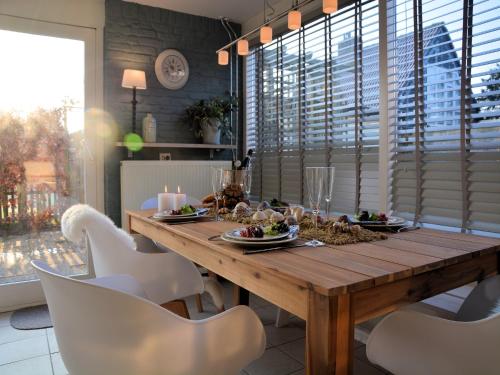 Un comedor con una mesa de madera y sillas blancas. en Holiday Home Noordwijk near the Beach, en Noordwijkerhout