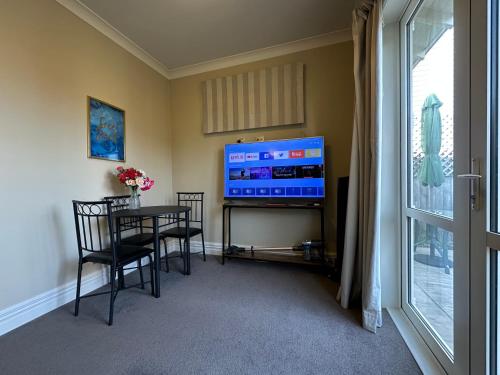 a dining room with a table and a flat screen tv at Cosy & new CNZhouse with yard in Christchurch