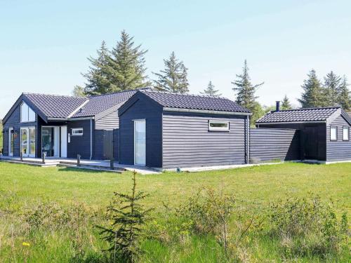 ein Haus auf einem Feld mit einem Rasenplatz in der Unterkunft 10 person holiday home in Brovst-By Traum in Brovst